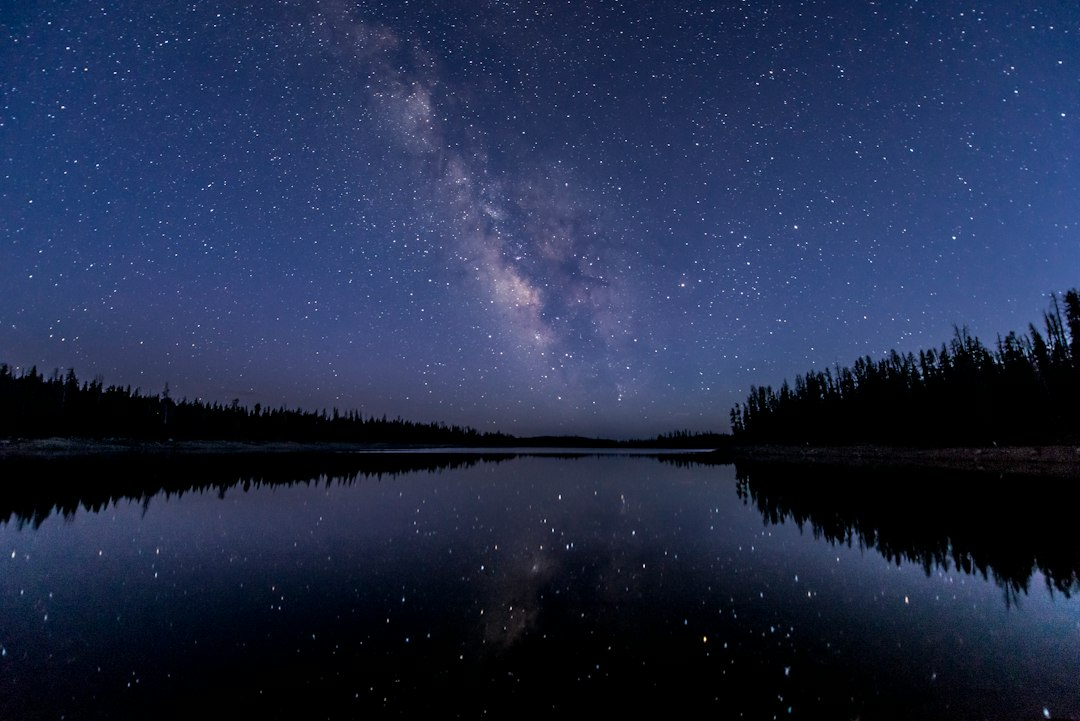 Milky Way stretching over a still mountain lake at night, a picture of the great signs in the sky in Revelation 12 and 13