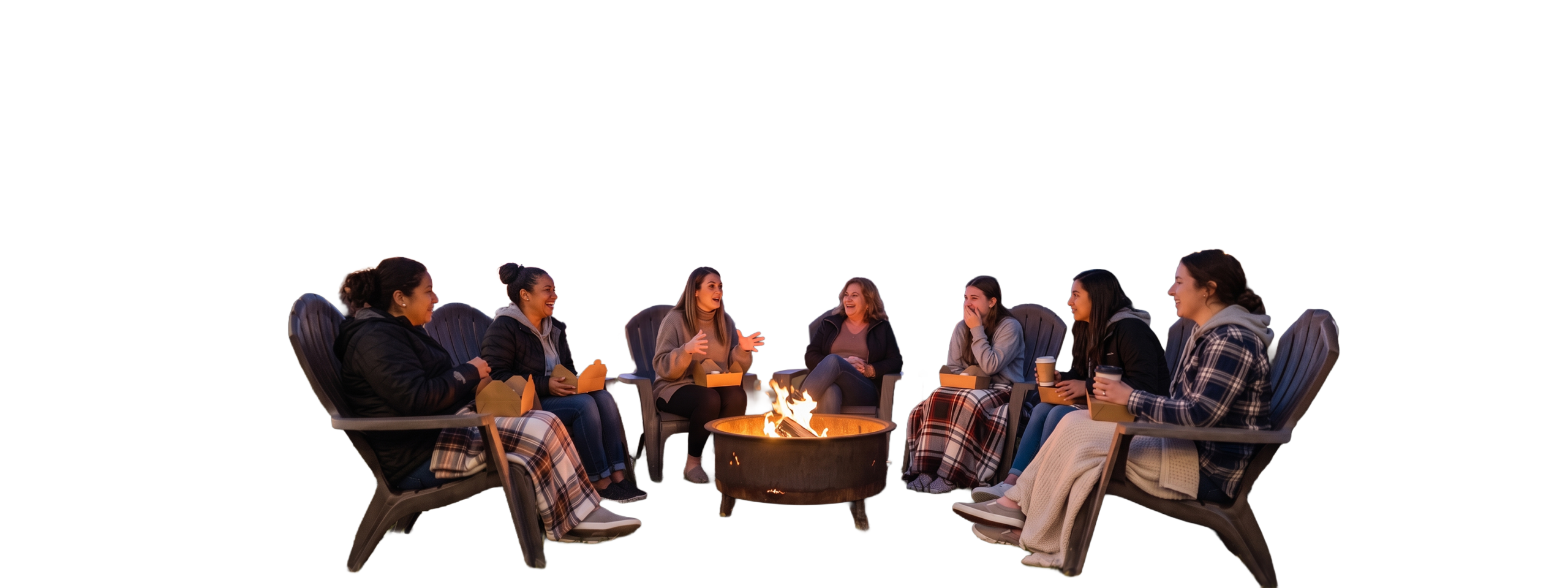 Women laughing together around a fire pit at dusk